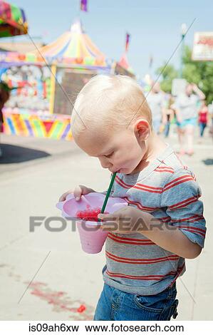 Male toddler concentrating on juice drink at funfair View Large Photo Image Stock Photo - Male toddler concentrating on juice drink at funfair. Fotosearch