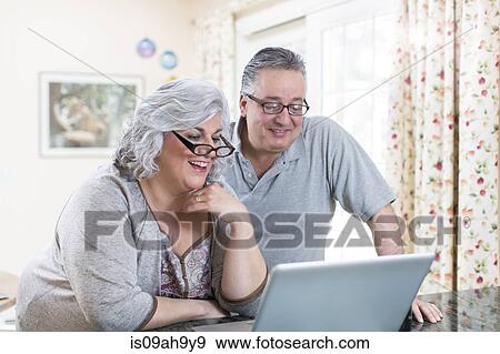 Mature couple at home using laptop View Large Photo Image Stock Photo - Mature couple at home using laptop. Fotosearch