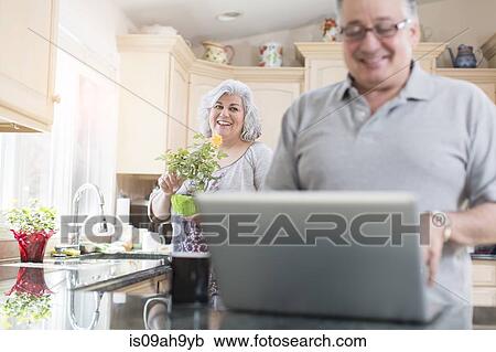 Mature couple in kitchen using laptop View Large Photo Image Stock Image - Mature couple in kitchen using laptop. Fotosearch