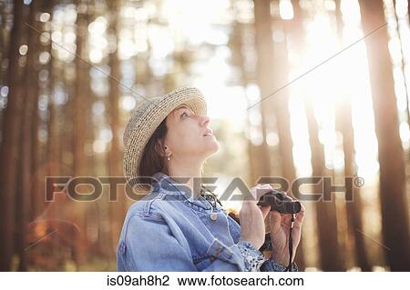 Stock Image - Mature female bird watcher in forest. Fotosearch