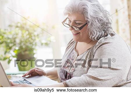 Mature woman at home using laptop View Large Photo Image Stock Photography - Mature woman at home using laptop. Fotosearch