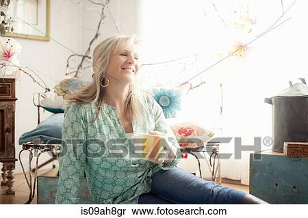 Mature woman sitting on floor in living room View Large Photo Image Stock Photography - Mature woman sitting on floor in living room. Fotosearch