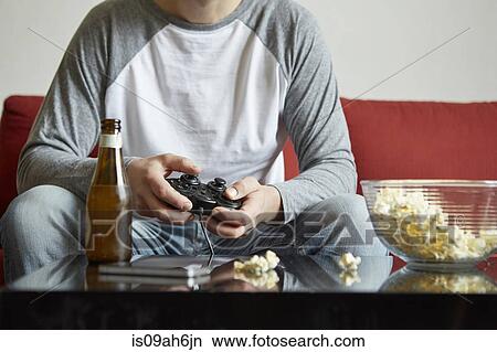 Mid adult man sitting on sofa using computer game control View Large Photo Image Picture - Mid adult man sitting on sofa using computer game control. Fotosearch