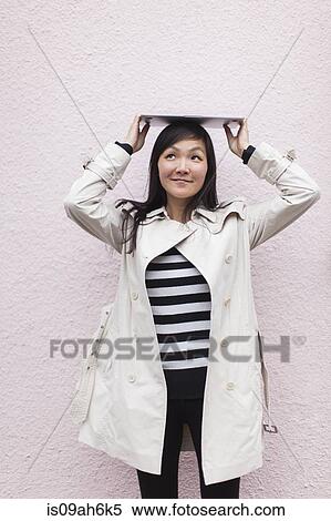 Mid adult woman holding up digital tablet on her head View Large Photo Image Stock Photography - Mid adult woman holding up digital tablet on her head. Fotosearch