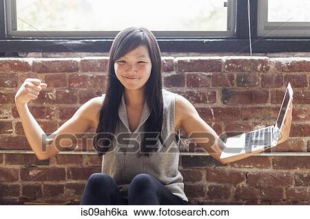 Mid adult woman sitting on floor balancing laptop on arm View Large Photo Image Stock Image - Mid adult woman sitting on floor balancing laptop on arm. Fotosearch