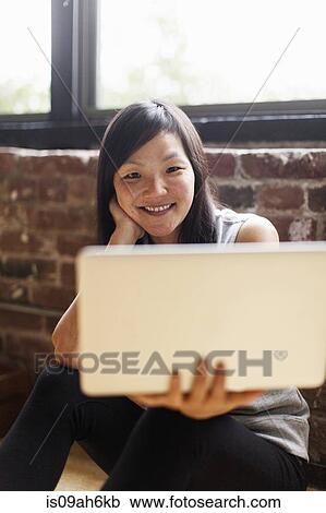 Mid adult woman sitting on floor holding laptop View Large Photo Image Stock Image - Mid adult woman sitting on floor holding laptop. Fotosearch