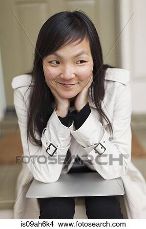 Mid adult woman sitting with digital tablet on her lap View Large Photo Image Picture - Mid adult woman sitting with digital tablet on her lap. Fotosearch