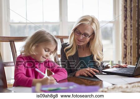Mother and young daughter doing work and homework in dining room View Large Photo Image Stock Photo - Mother and young daughter doing work and homework in dining room. Fotosearch