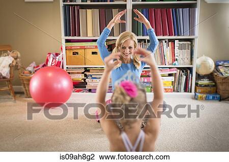 Stock Image - Mother and young daughter practicing ballet in sitting room. Fotosearch