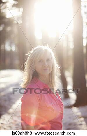 Stock Photo - Portrait of mature woman in sunlit forest. Fotosearch