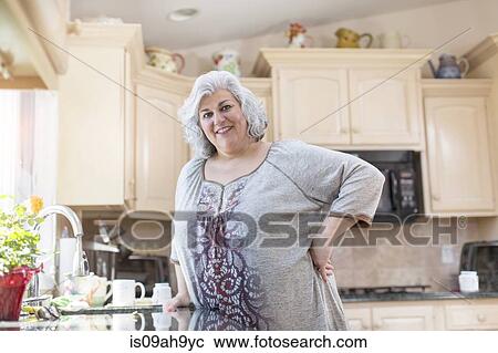 Portrait of mature woman with hand on hip in kitchen View Large Photo Image Stock Image - Portrait of mature woman with hand on hip in kitchen. Fotosearch