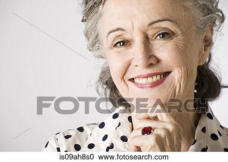 Stock Image - Portrait of senior woman, hand on chin, smiling. Fotosearch