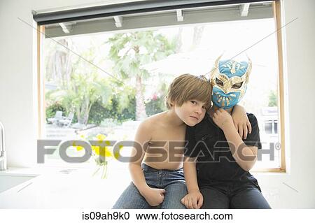 Stock Image - Portrait of two brothers, one bare chested and one masked. Fotosearch