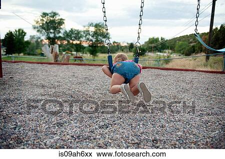 Rear view of female toddler lying on park swing View Large Photo Image Stock Photo - Rear view of female toddler lying on park swing. Fotosearch