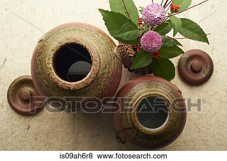 Stock Photo - Still life of ceramic jars and lids with vase of flowers and berries. Fotosearch