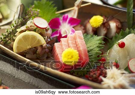 Stock Photo - Still life of rustic food with sliced raw fish, fruit and flowers. Fotosearch