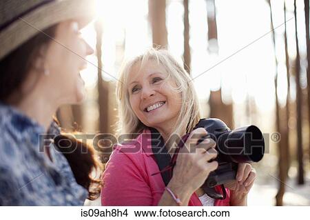 Picture - Two mature women with digital camera in forest. Fotosearch