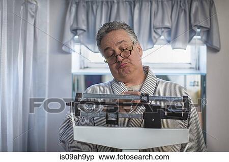 Unhappy mature man on bathroom weighing scales View Large Photo Image Stock Photography - Unhappy mature man on bathroom weighing scales. Fotosearch