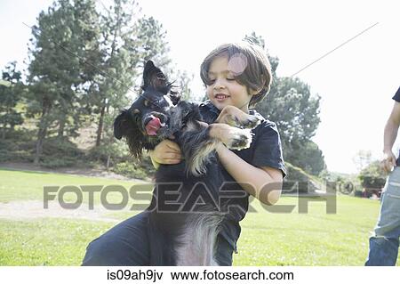 Stock Photo - Young boy in park playing with his dog. Fotosearch