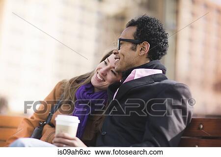 Stock Image - Young couple on park bench, New York, USA. Fotosearch