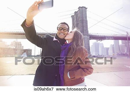Young couple taking self portrait next to Brooklyn Bridge, New York, USA View Large Photo Image Stock Photo - Young couple taking self portrait next to Brooklyn Bridge, New York, USA. Fotosearch