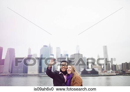Stock Image - Young couple taking selfie with Manhattan skyline, New York, USA. Fotosearch