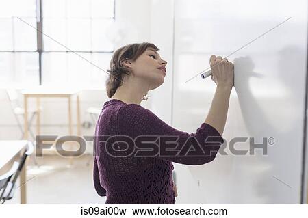 Stock Photo - Young female designer drawing on whiteboard. Fotosearch