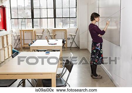 Young female designer drawing on whiteboard in design studio View Large Photo Image Stock Photo - Young female designer drawing on whiteboard in design studio. Fotosearch