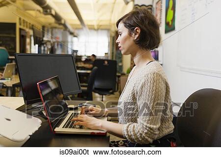 Young female designer using laptop in studio View Large Photo Image Stock Photograph - Young female designer using laptop in studio. Fotosearch