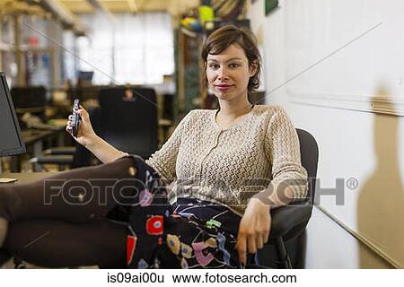 Stock Photograph - Young female designer with feet up in design studio. Fotosearch