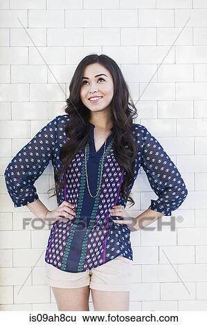 Young woman standing with hands on hips View Large Photo Image Stock Photograph - Young woman standing with hands on hips. Fotosearch