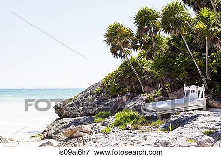 Stock Photo - Bed on rocks at beach in Tulum, Mexico. Fotosearch