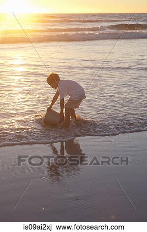 Stock Image - Boy fetching sea water with bucket. Fotosearch