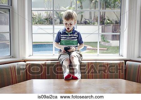 Boy playing handheld video game View Large Photo Image Stock Image - Boy playing handheld video game. Fotosearch