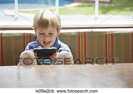 Stock Image - Boy playing handheld video game. Fotosearch