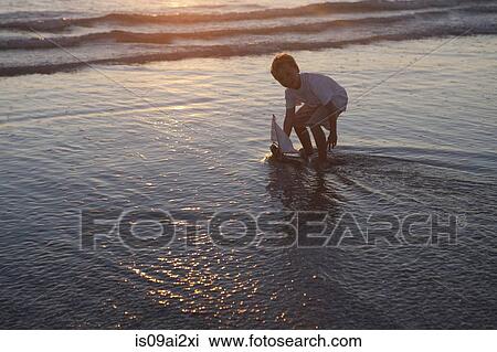Boy playing toy boat on beach View Large Photo Image Stock Image - Boy playing toy boat on beach. Fotosearch