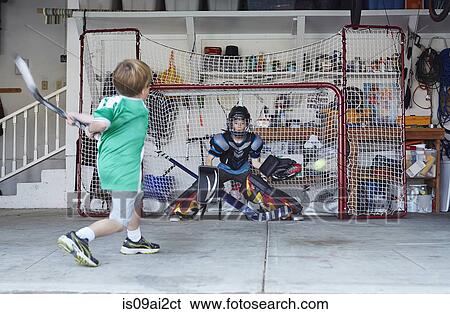 Boys playing hockey in garage View Large Photo Image Stock Photograph - Boys playing hockey in garage. Fotosearch