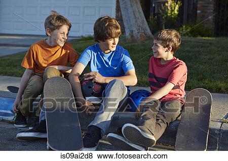Boys sitting on pavement with skateboards View Large Photo Image Stock Photo - Boys sitting on pavement with skateboards. Fotosearch