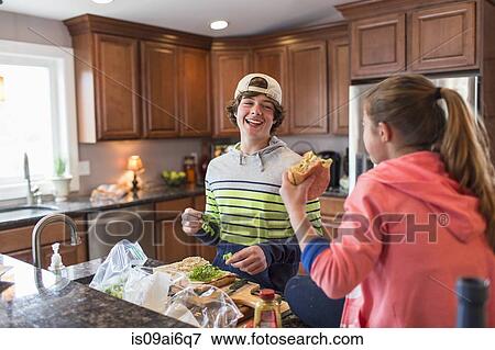 Stock Photo - Brother and sister in kitchen preparing sandwich. Fotosearch