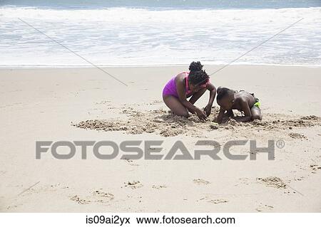 Stock Photo - Children digging in sand on beach. Fotosearch