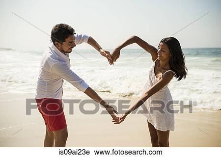Couple making heart shape with arms on Arpoador beach, Rio De Janeiro, Brazil View Large Photo Image Stock Image - Couple making heart shape with arms on Arpoador beach, Rio De Janeiro, Brazil. Fotosearch