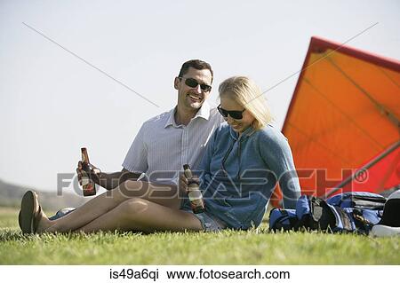 Couple relaxing with beer, hang glider in background View Large Photo Image Stock Image - Couple relaxing with beer, hang glider in background. Fotosearch