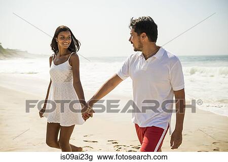 Stock Image - Couple strolling on Arpoador beach, Rio De Janeiro, Brazil. Fotosearch