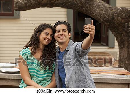 Couple taking self portrait photograph using smartphone View Large Photo Image Picture - Couple taking self portrait photograph using smartphone. Fotosearch