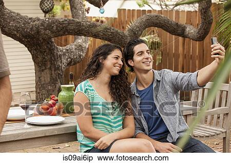 Couple taking self portrait photograph using smartphone View Large Photo Image Stock Photography - Couple taking self portrait photograph using smartphone. Fotosearch