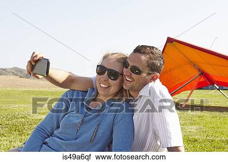 Couple taking selfie, hang glider in background View Large Photo Image Stock Image - Couple taking selfie, hang glider in background. Fotosearch
