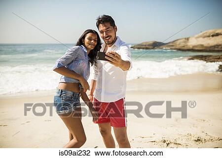 Couple taking selfie on smartphone, Arpoador beach, Rio De Janeiro, Brazil View Large Photo Image Stock Image - Couple taking selfie on smartphone, Arpoador beach, Rio De Janeiro, Brazil. Fotosearch