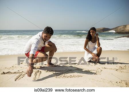 Couple writing in sand on Arpoador beach, Rio De Janeiro, Brazil View Large Photo Image Stock Photo - Couple writing in sand on Arpoador beach, Rio De Janeiro, Brazil. Fotosearch