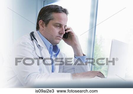 Stock Image - Doctor using mobile phone. Fotosearch