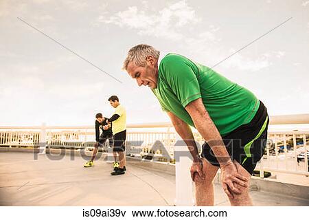Stock Photo - Exhausted male runners taking a break from training. Fotosearch